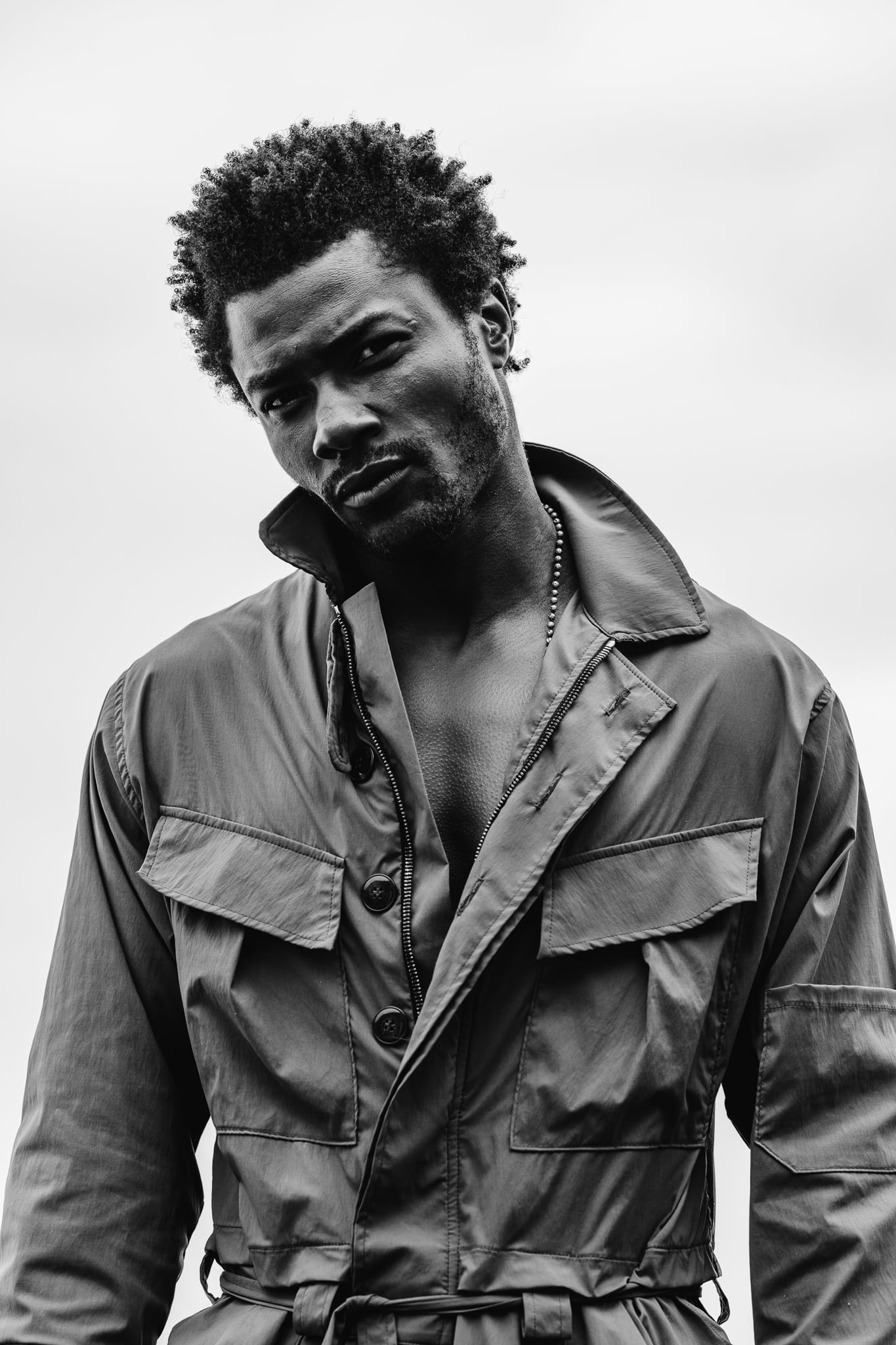 Copala model in an olive utility coverall with the collar turned up, black-and-white menswear portrait by Chauncey Scott, Malibu CA