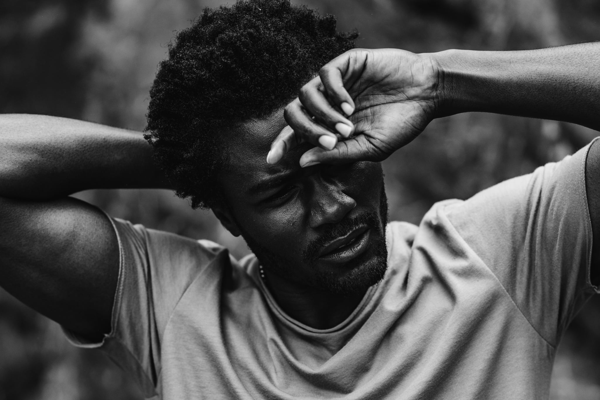 Copala model resting a forearm across his brow in a taupe tee, emotive black-and-white menswear portrait by Chauncey Scott, Malibu CA