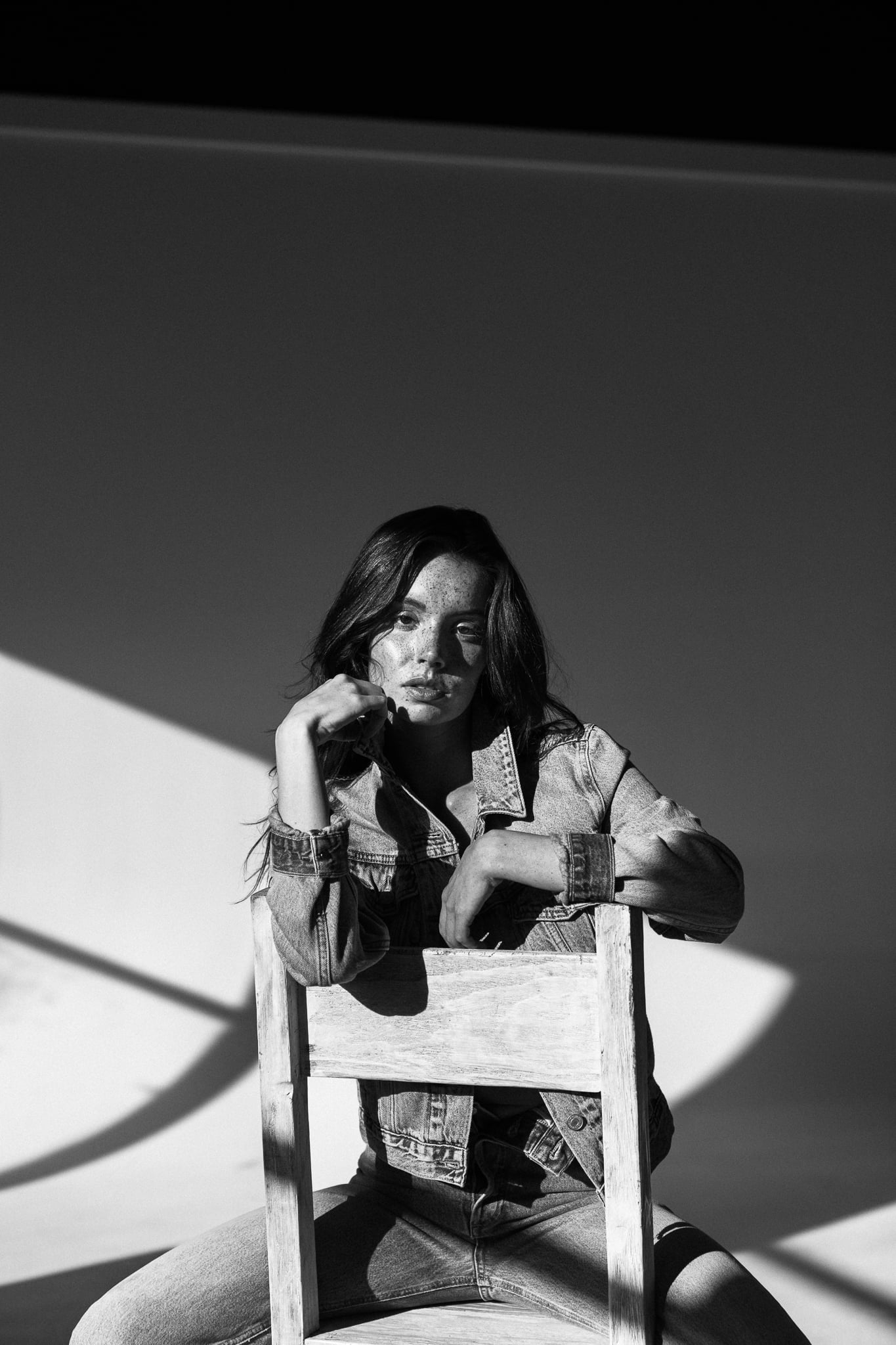 Lillian Connell perched behind a wooden chair in a Levi's denim jacket, black-and-white studio editorial by Chauncey Scott, Austin TX